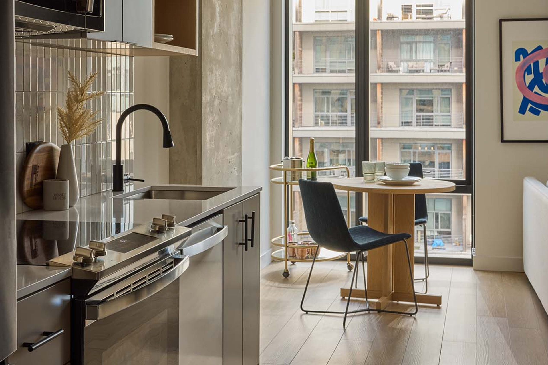 The kitchen and dining area of a Jessup House apartment. The dining area looks out a floor-to-ceiling window bringing comforting natural light into the room.