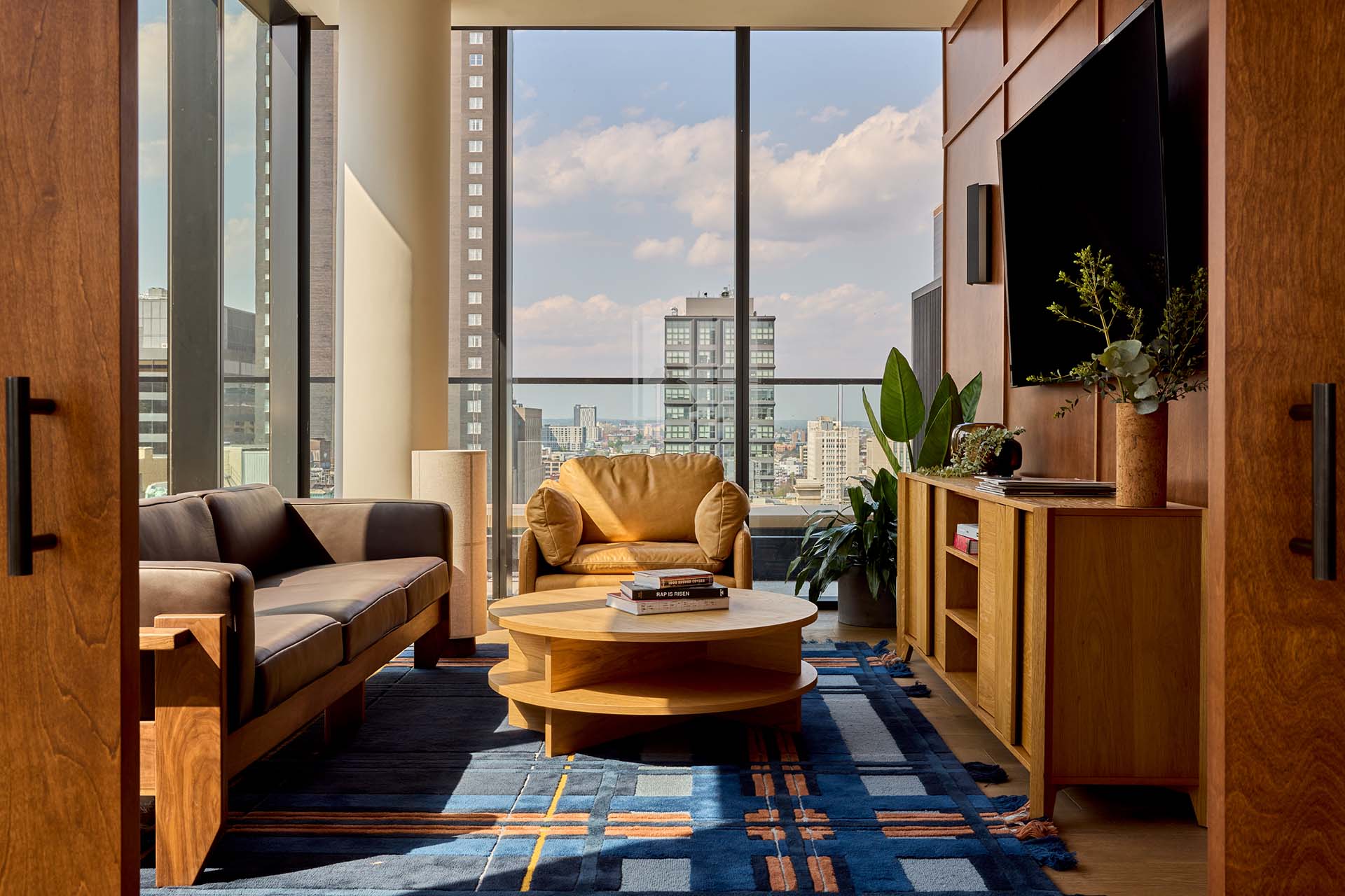 Resident lounge at Jessup House Apartments in Philadelphia, featuring couches and floor to ceiling windows.